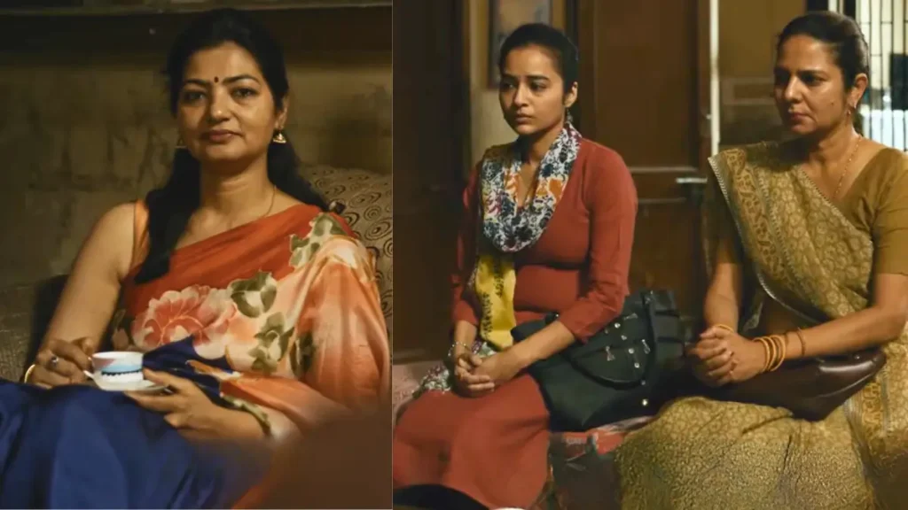 Three Indian women in sarees and kurtis having serious conversation in home living room, one holding teacup, emotional family moment